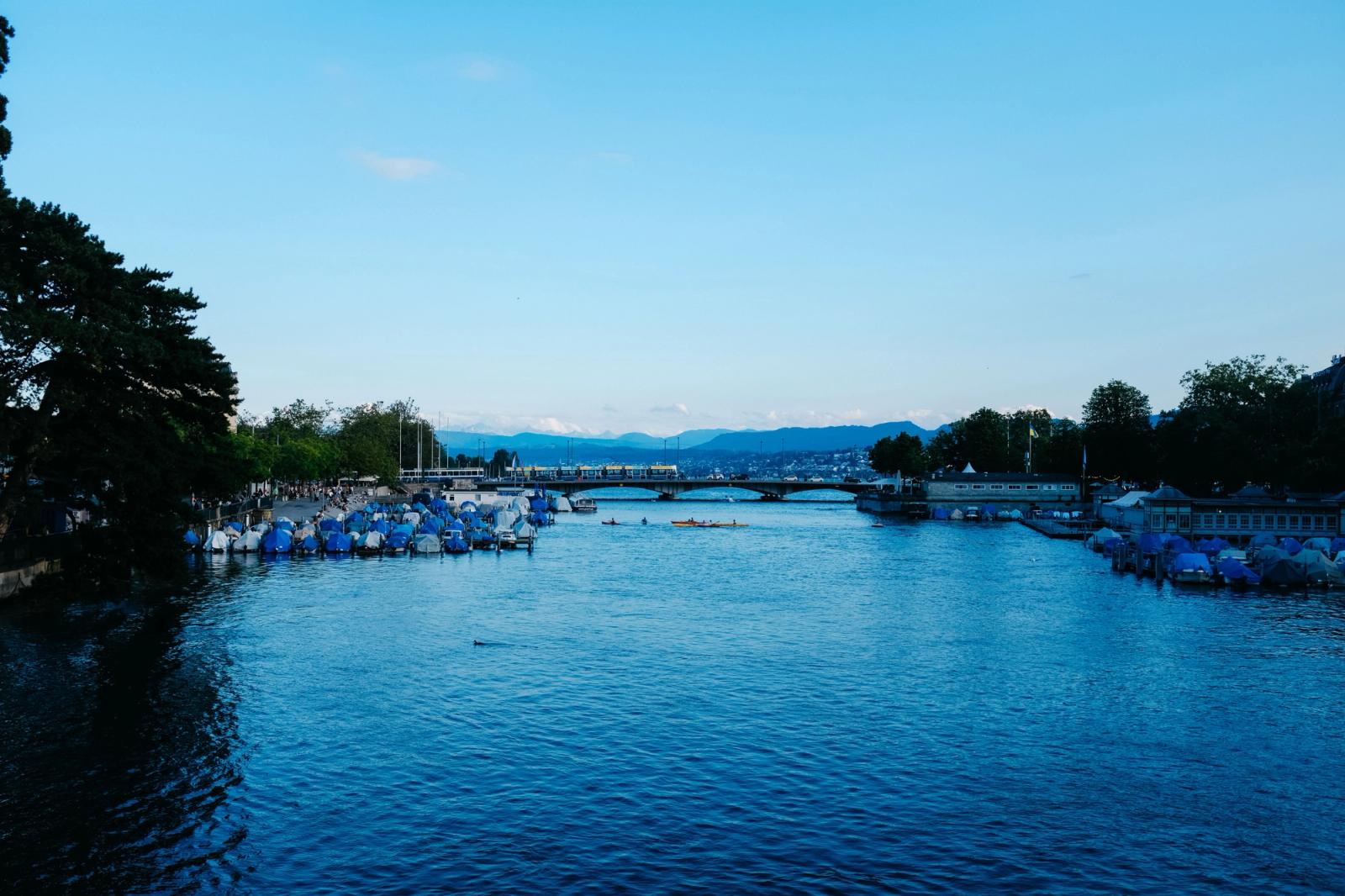 Picturesque view of Limmat River with moored boats and Zurich cityscape on a clear day