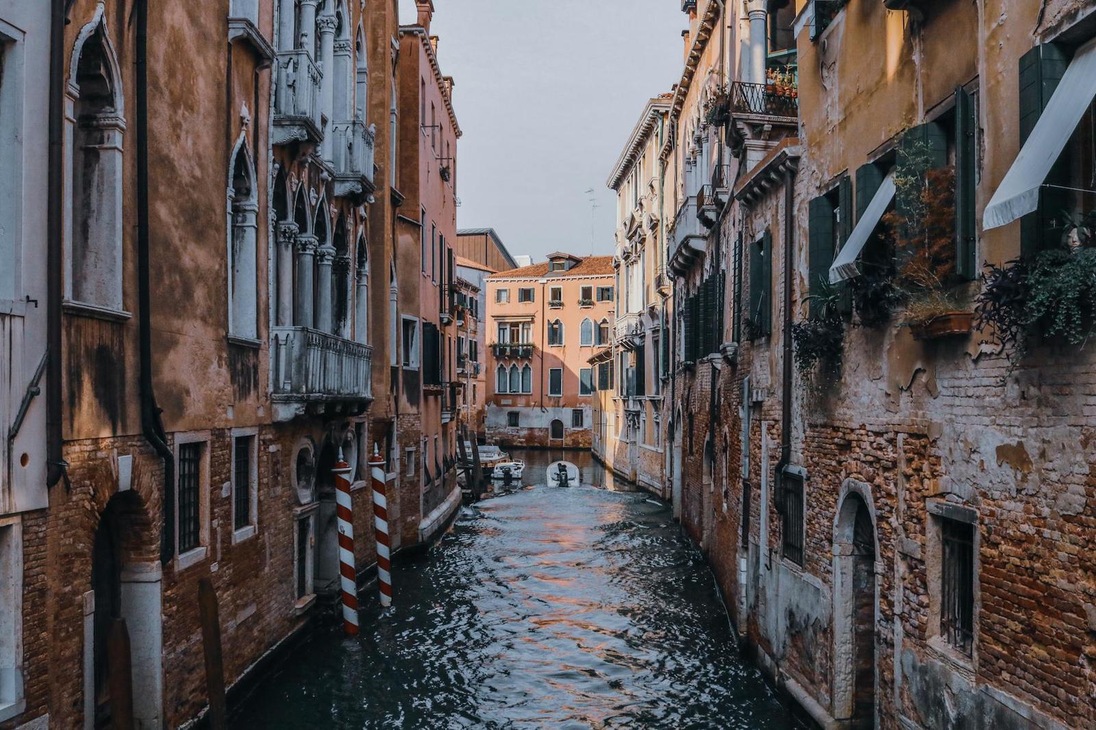 A narrow canal winding between weathered facades in an old European town