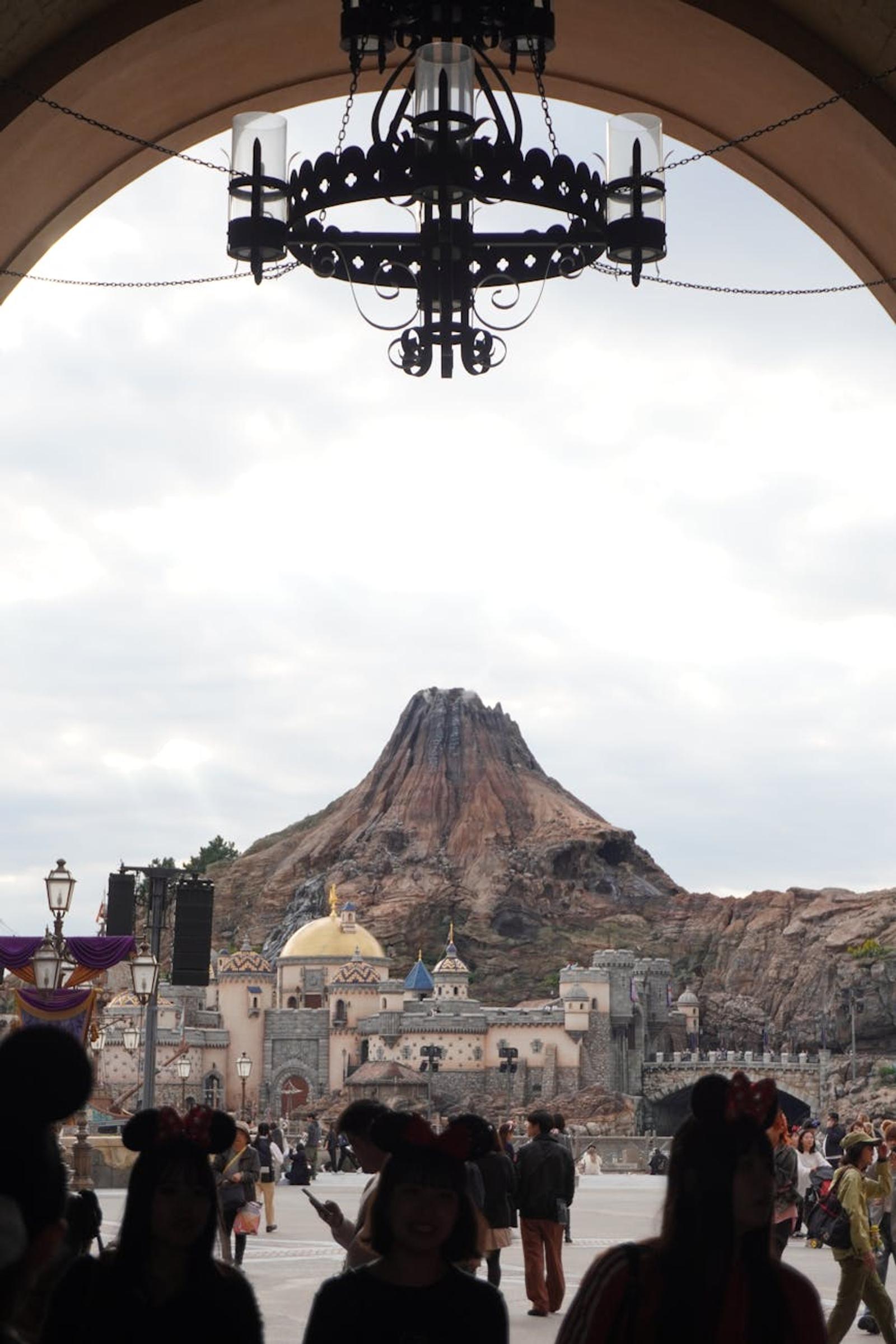 Silhouettes and enchanting view of Mount Prometheus at Tokyo DisneySea under an archway