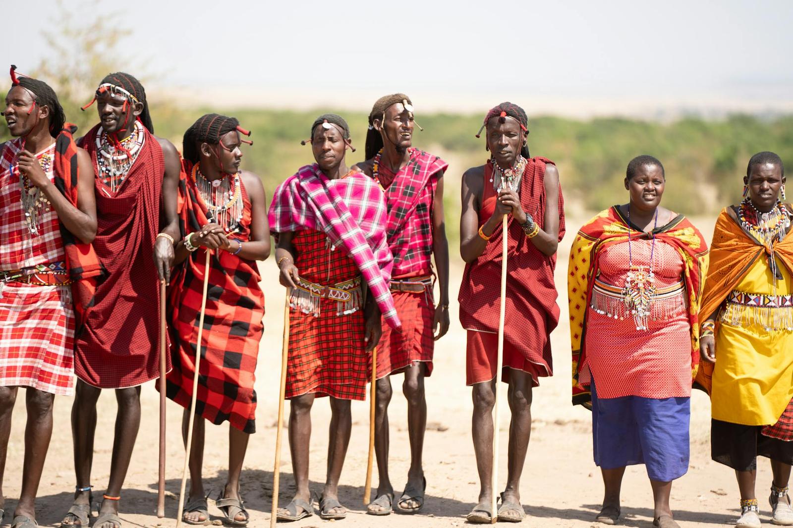 Maasai men and women in beaded jewelry and bright wraps standing in a line