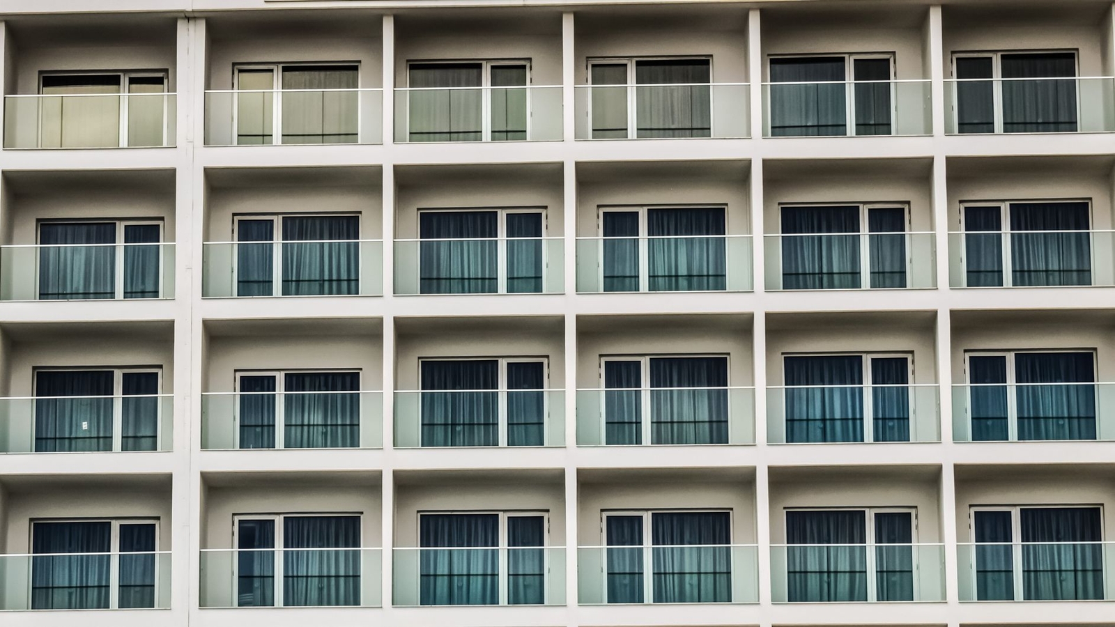 A repeating grid of curtained balcony windows on a hotel facade