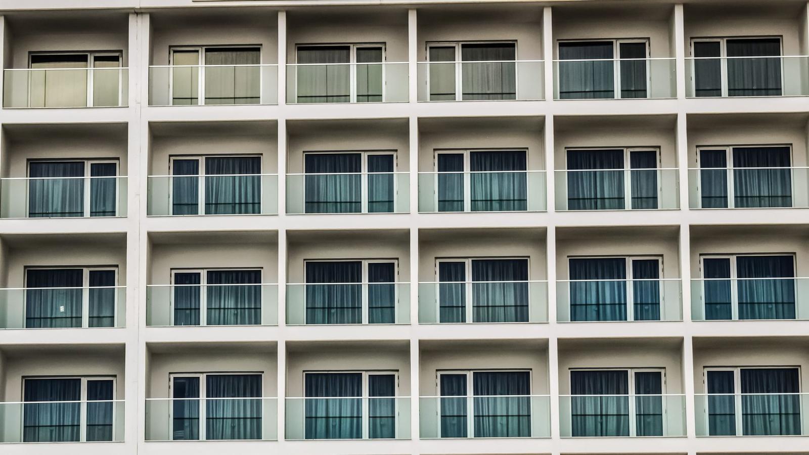A repeating grid of curtained balcony windows on a hotel facade