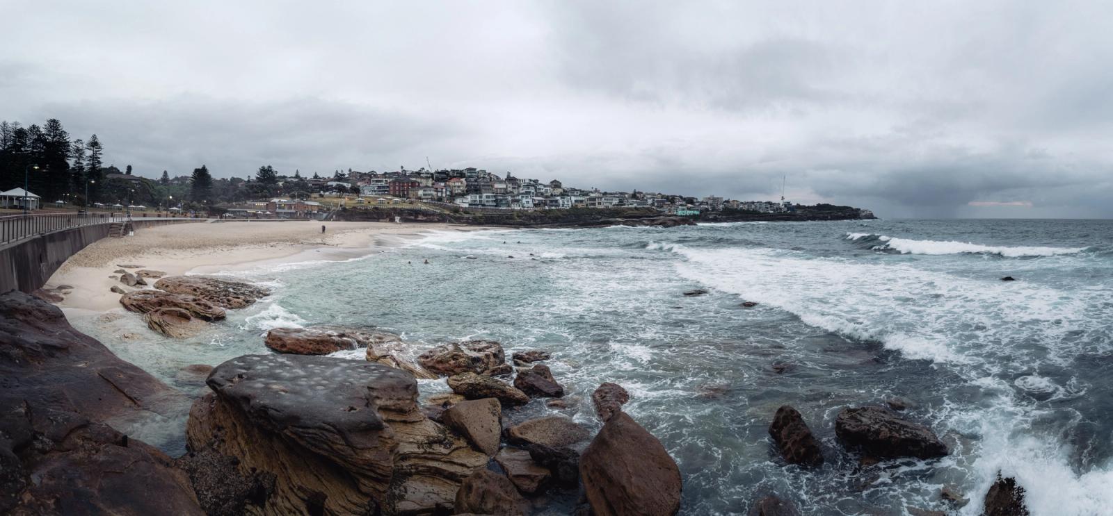 Panoramic scene of Bronte Beach with its rocky shore and cloudy sky in NSW, Australia