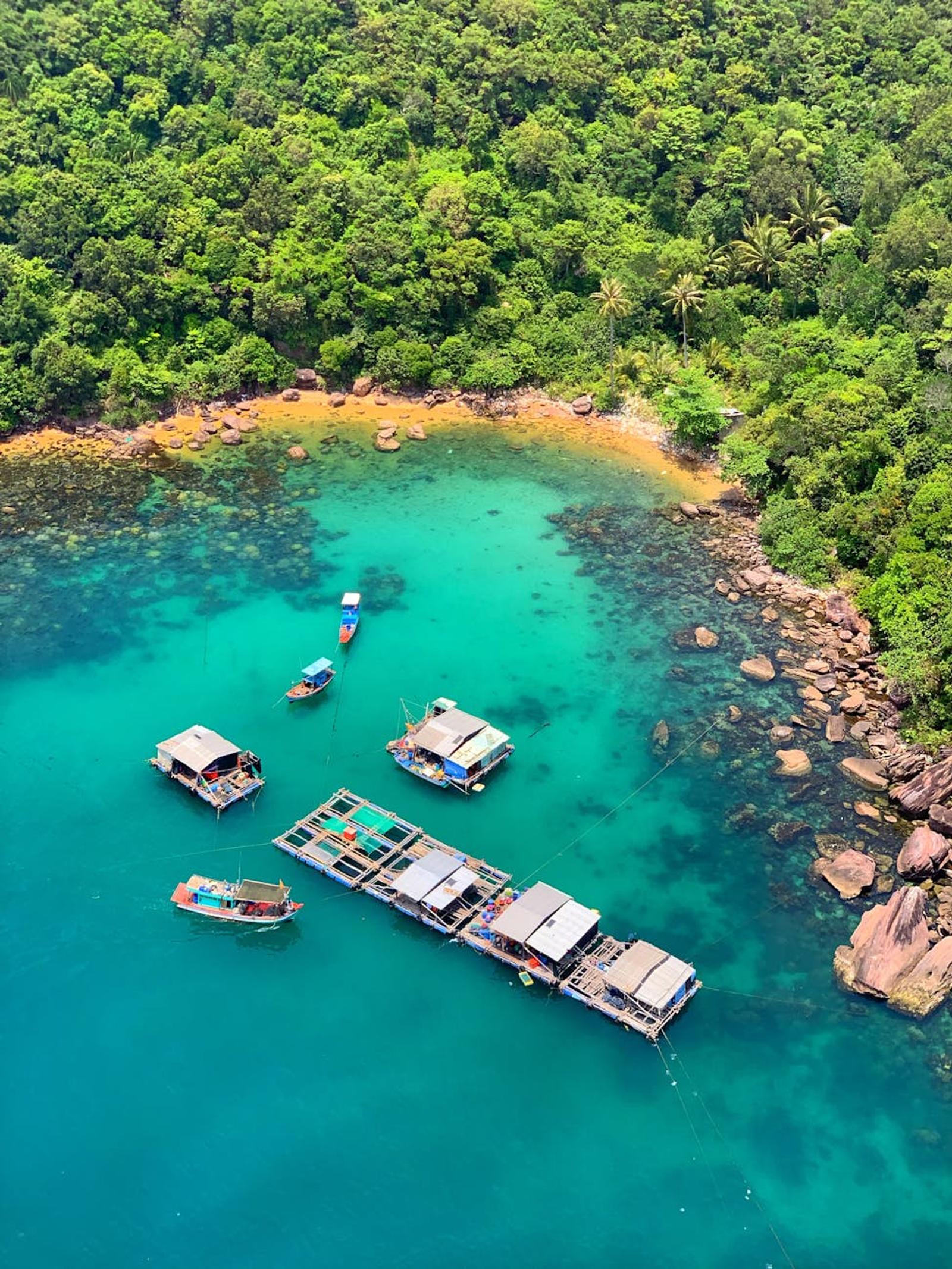 Boats moored in a turquoise cove ringed by dense jungle