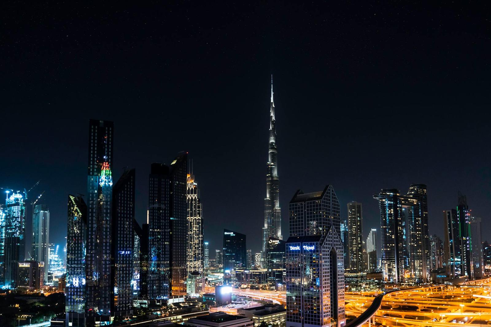 City skyline lit up at night around a needle-thin skyscraper