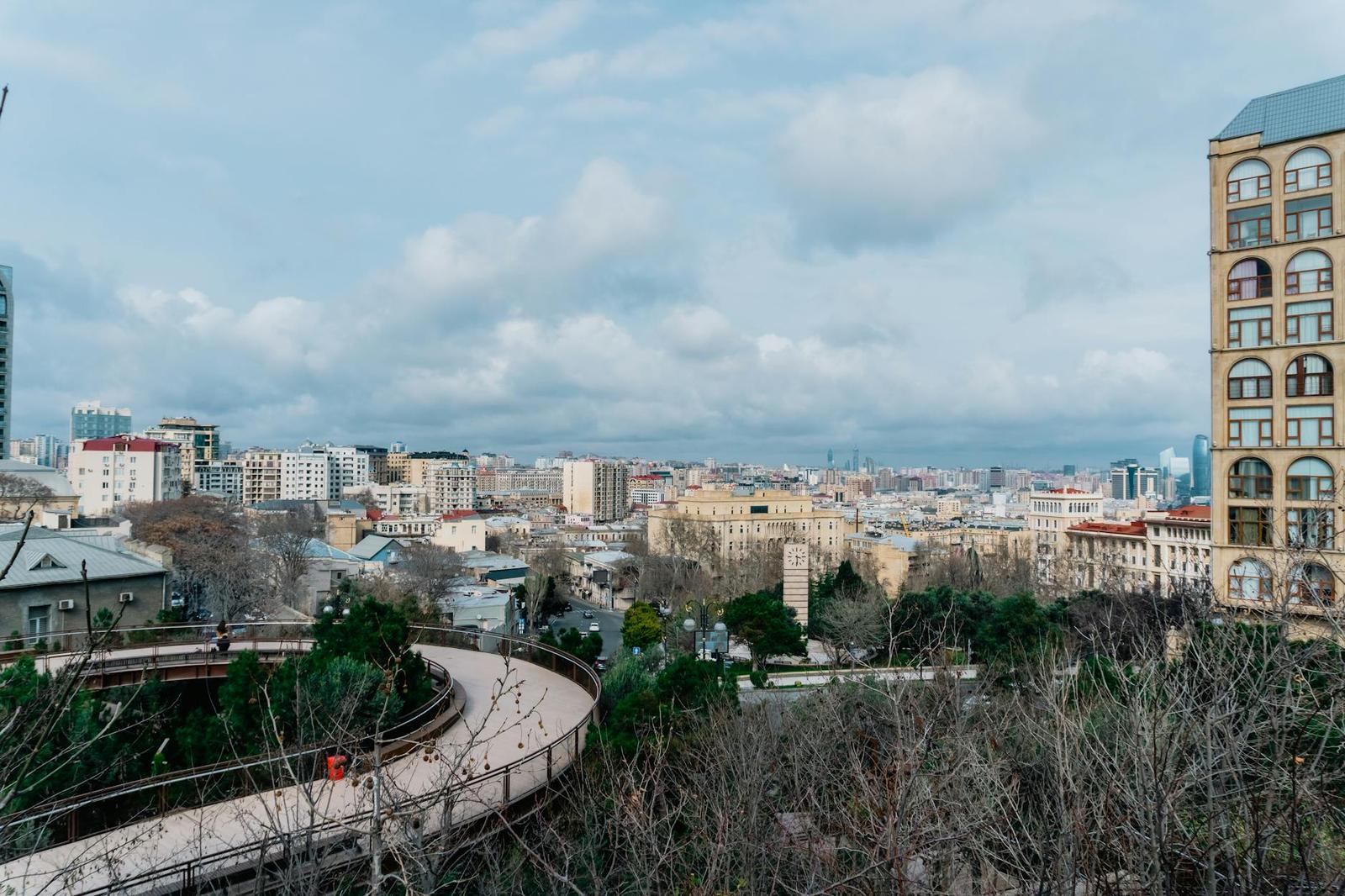 A curved elevated walkway winds above a hillside city skyline