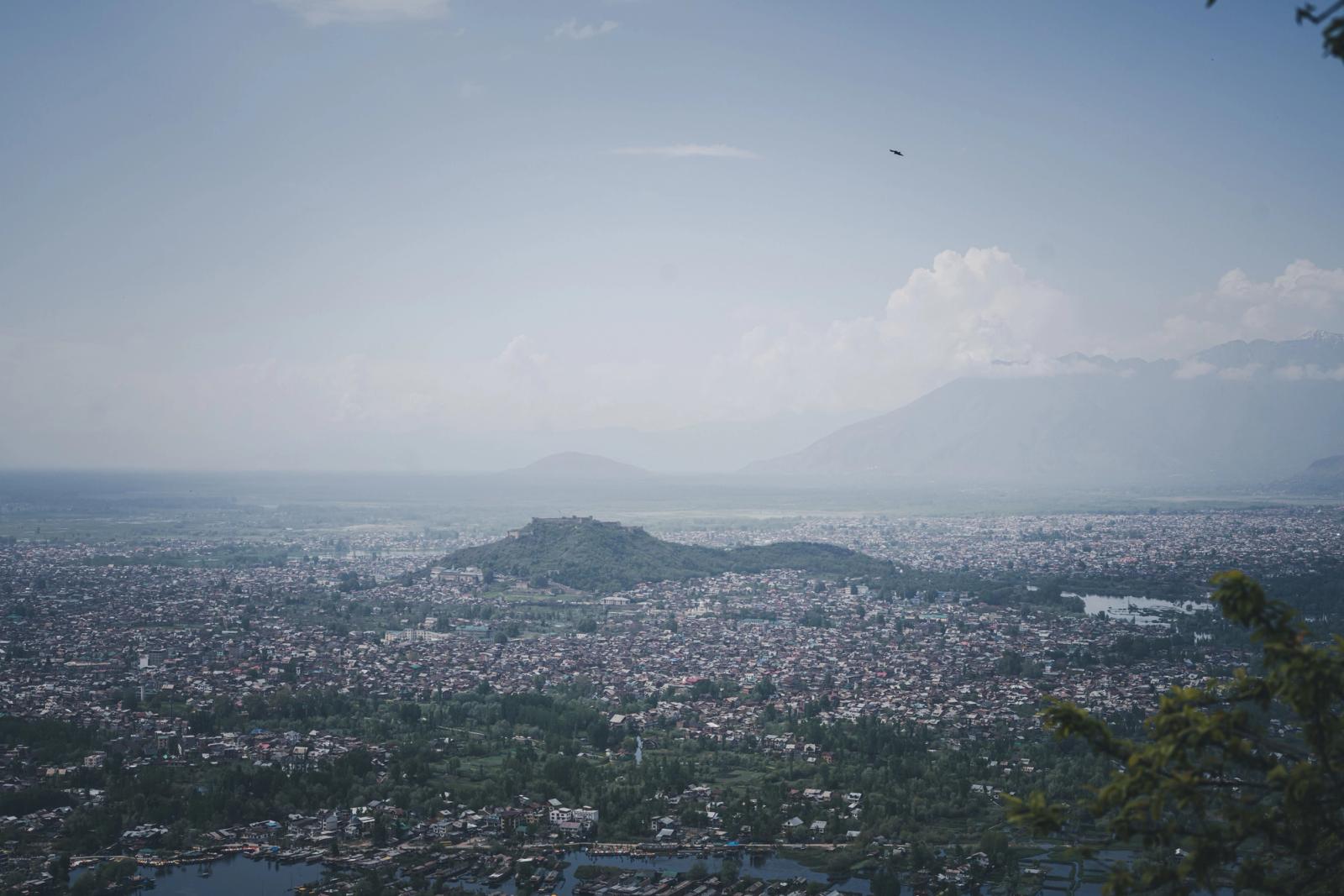 Stunning aerial shot of Srinagar cityscape with surrounding mountains under a clear blue sky