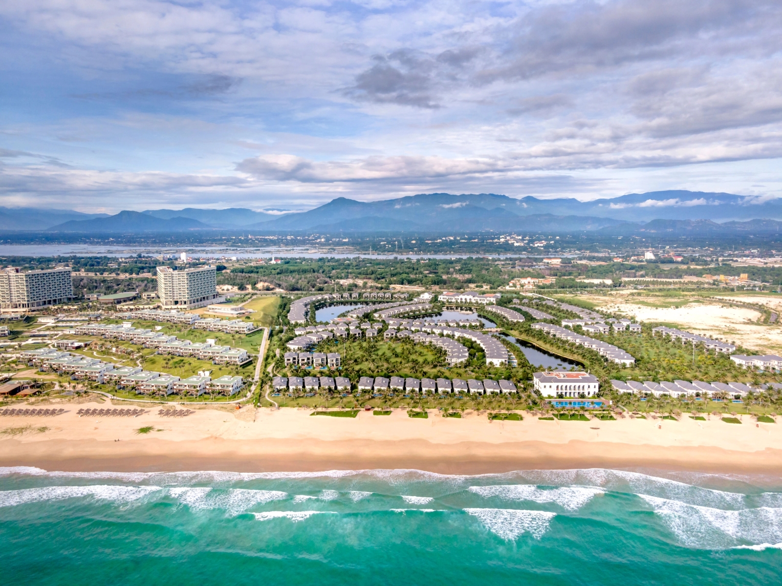 Stunning aerial view of a beachside resort with palm trees and modern architecture