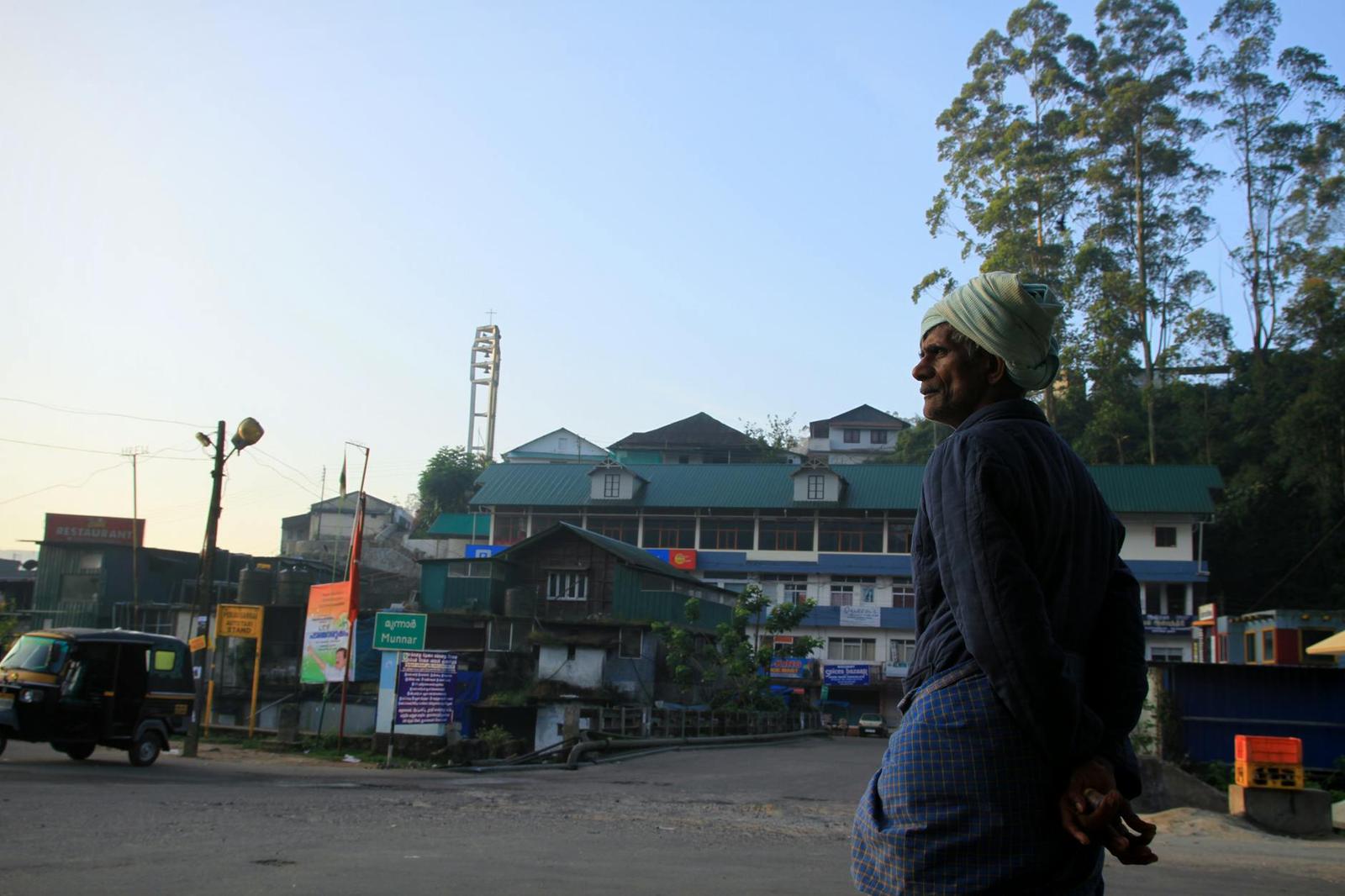 A South Asian man stands on a street in Munnar, India