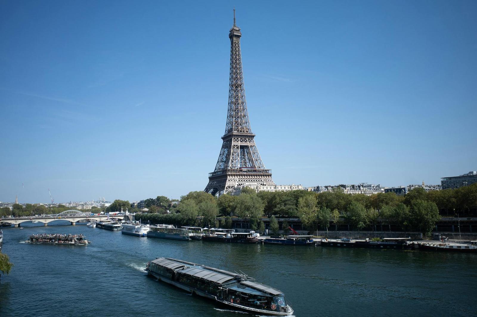 The Eiffel Tower on a clear day with a river cruise boat passing below