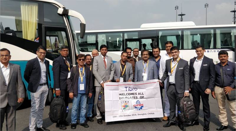 Group of People posing with a welcome banner near buses.