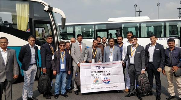 Group of People posing with a welcome banner near buses.