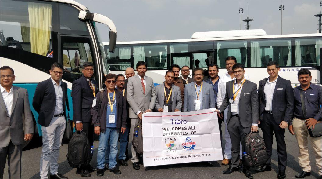 Group of People posing with a welcome banner near buses.