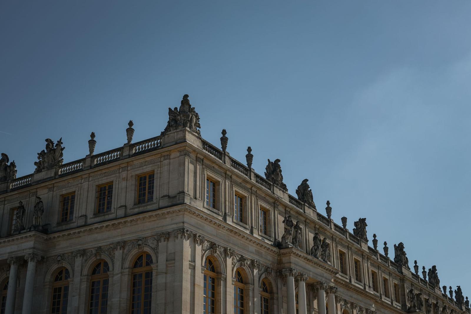 Ornate stone facade of a palace lined with rooftop statues