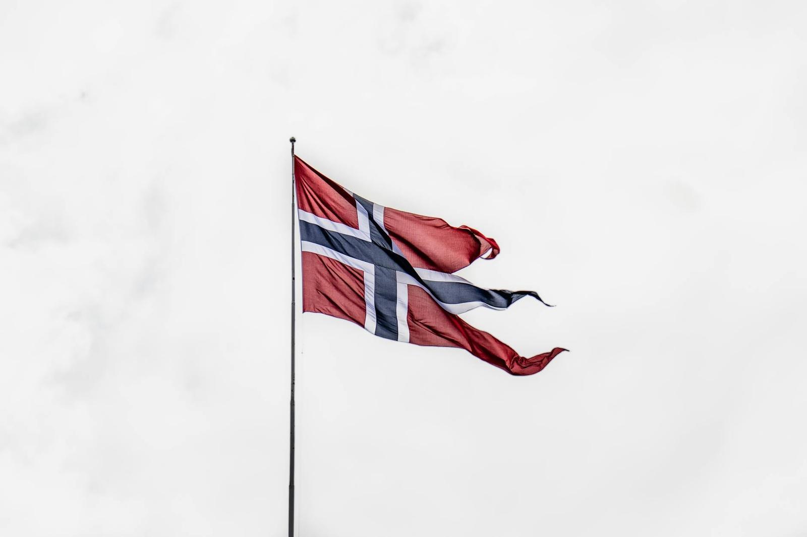 Norwegian flag flying against a pale overcast sky