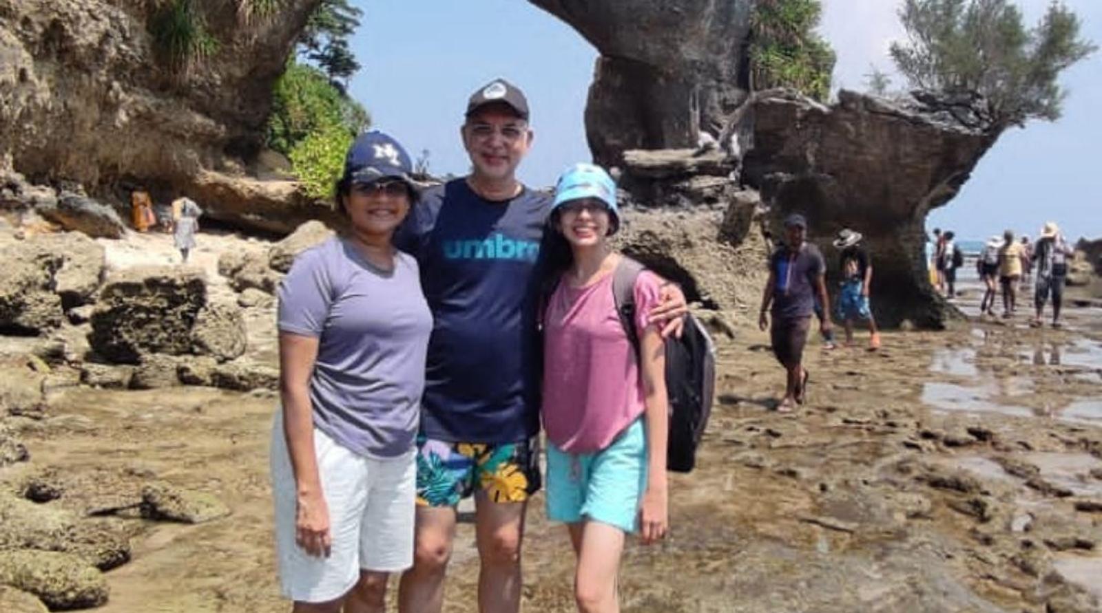 Three people stand on the beach 