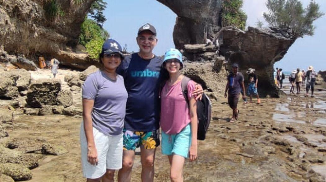 Three people stand on the beach