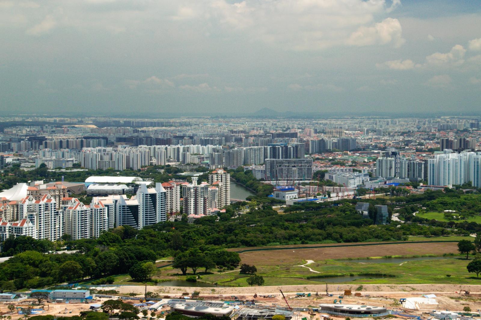 A panoramic aerial view of Singapore showcasing dense urban buildings amidst lush greenery
