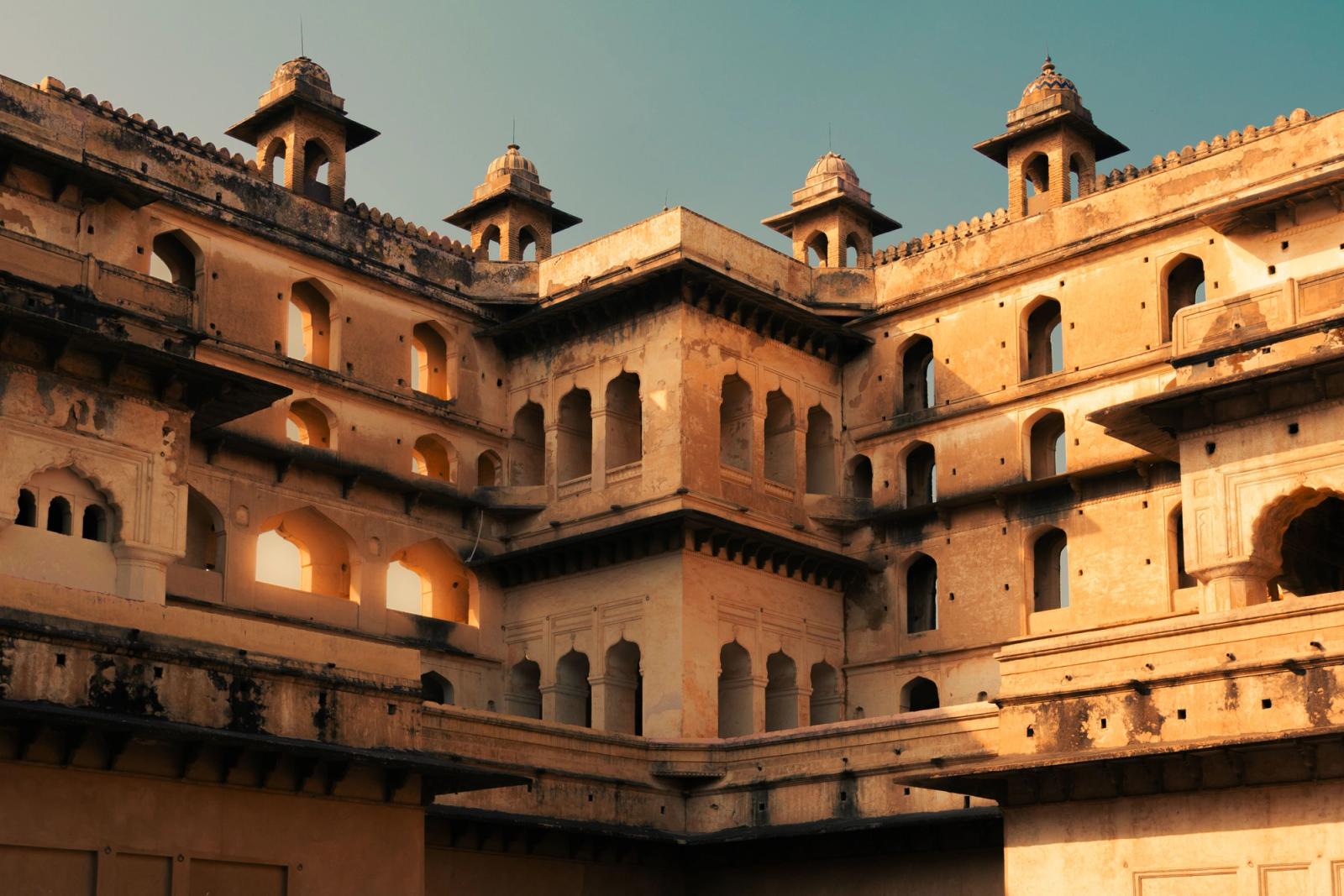 A sandstone palace facade with domed corner turrets and arched windows