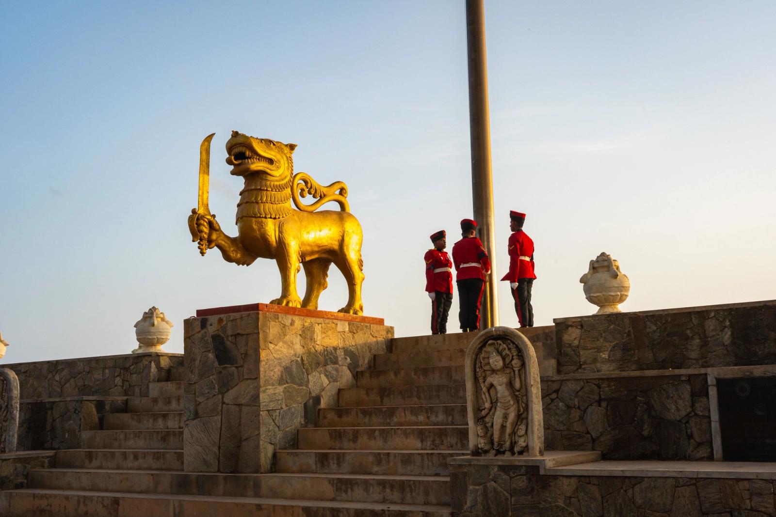 Sri Lankan soldiers in ceremonial dress beside golden lion statue in Colombo