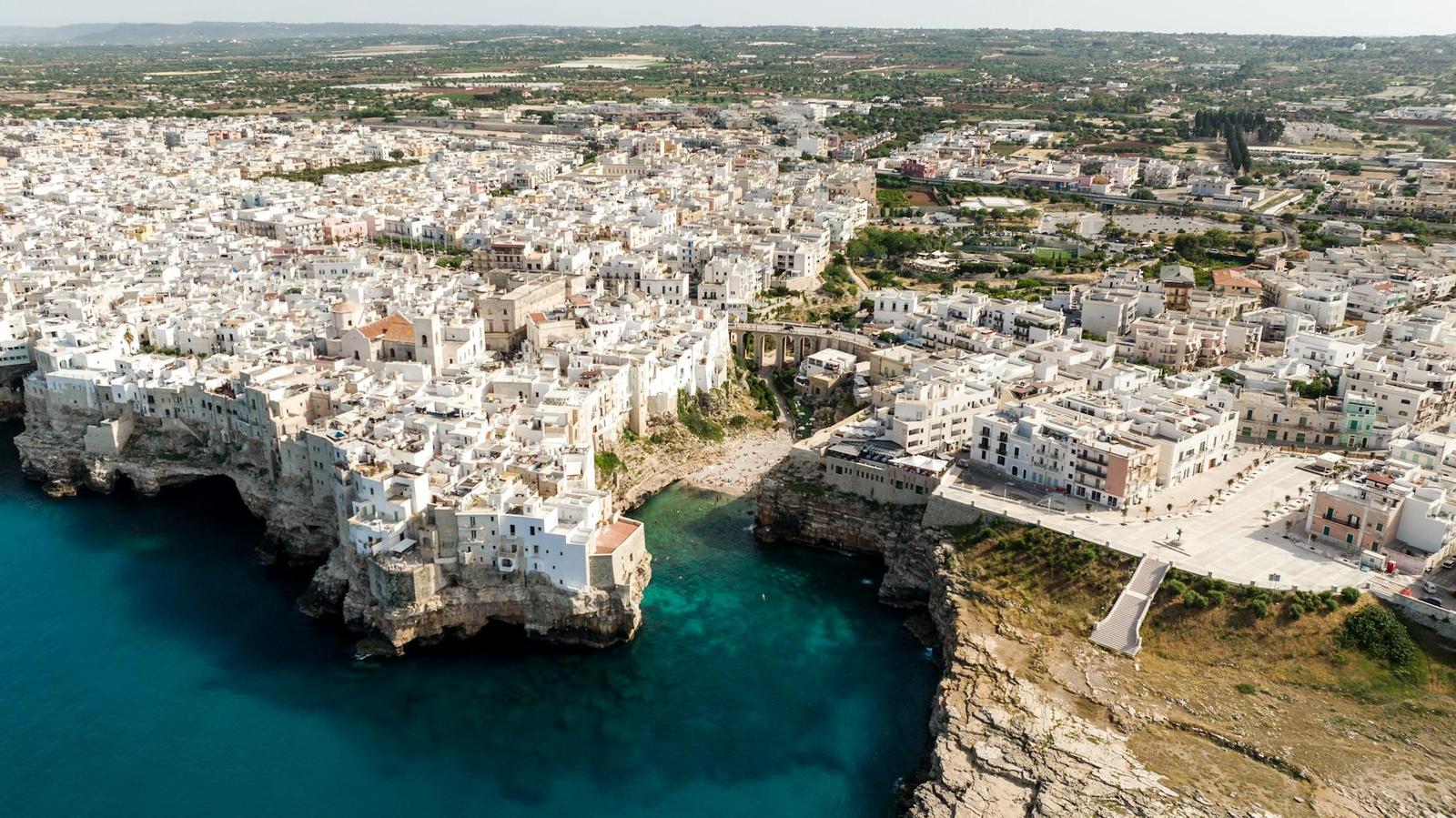 Aerial view of whitewashed cliffside town wrapped around a rocky cove