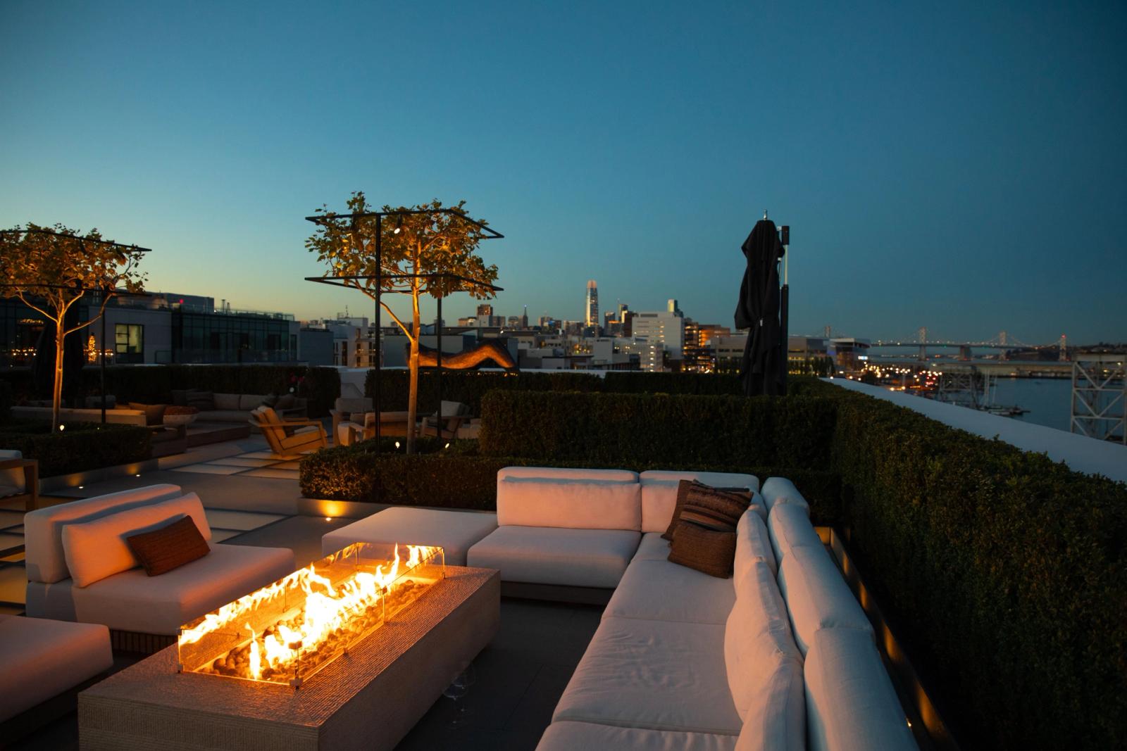 Luxury rooftop terrace in San Francisco with a fire pit and stunning cityscape view at dusk