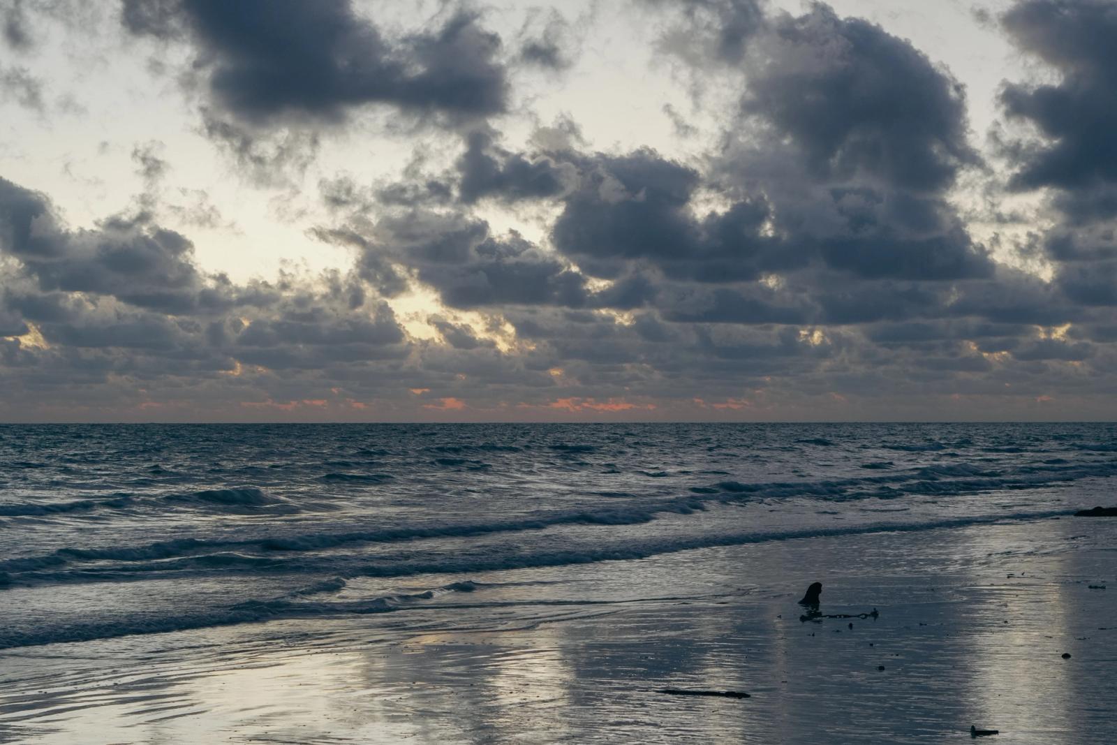 Calm waves and dramatic clouds create a picturesque sunset at Andaman Islands