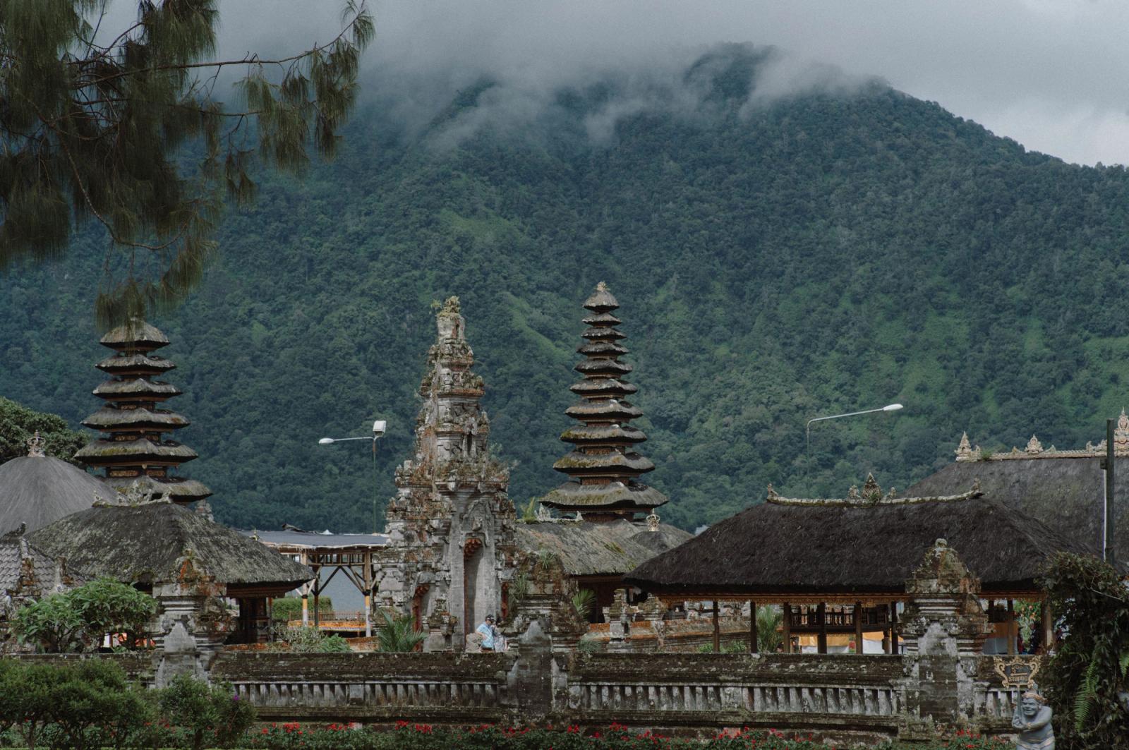 A beautiful temple in Bali with mountains and lush greenery in the background, showcasing unique architecture