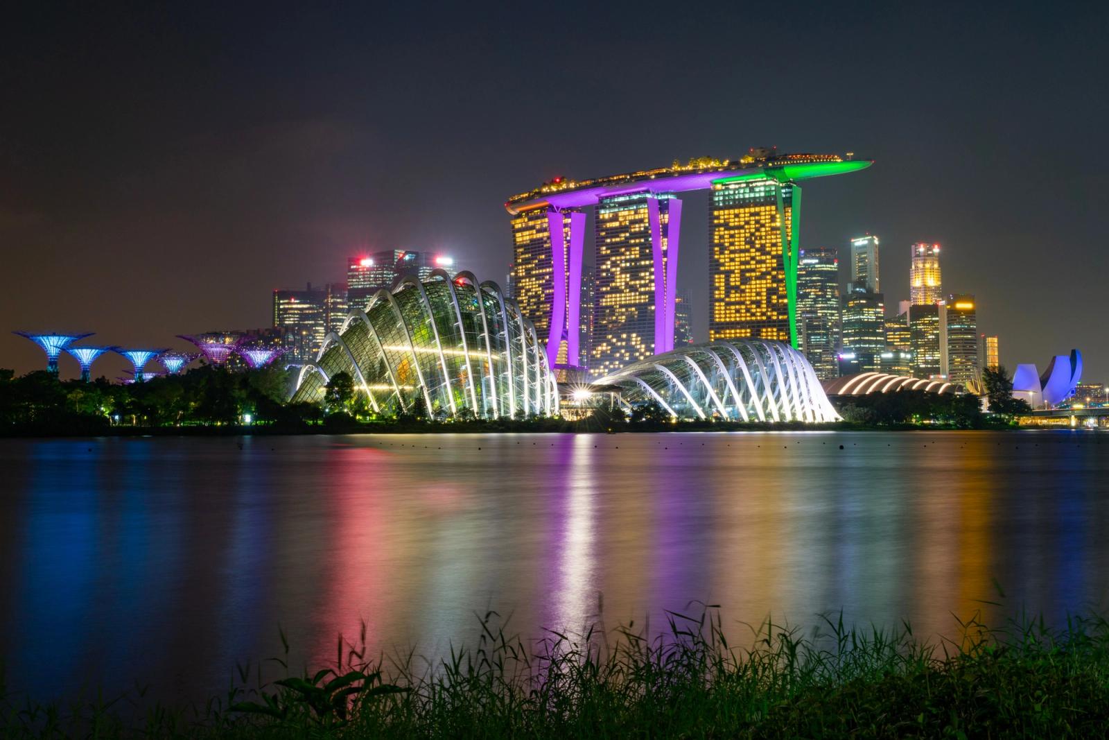 Stunning view of Singapore's Marina Bay at night, capturing illuminated landmarks and the dazzling skyline reflecting on water