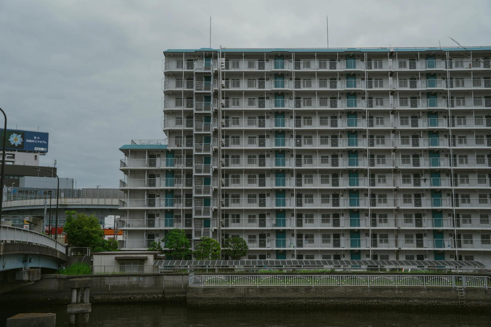Multi-story residential building beside a canal in Tokyo, Japan, showcasing urban architecture
