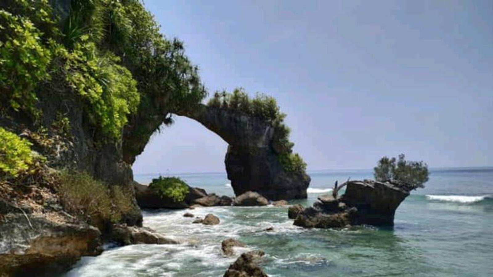 Stunning aerial view of a natural rock arch over turquoise ocean waves