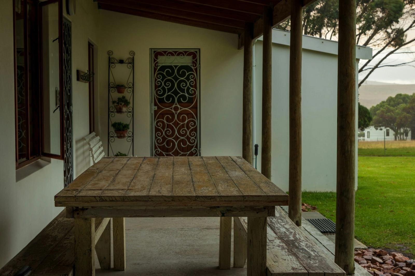 A covered stone patio with a wooden table beside an ornate iron door