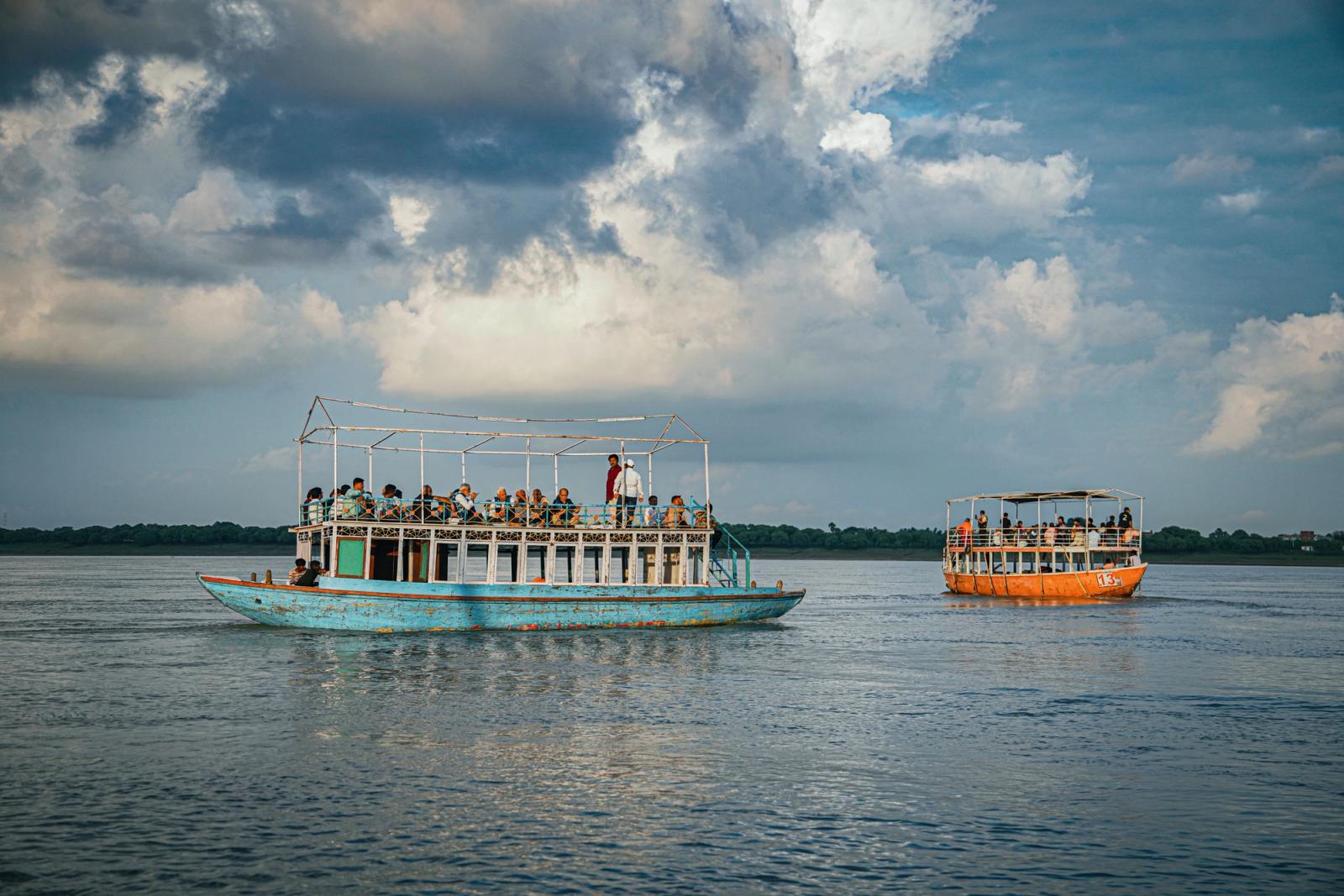 Tourist boats sailing on the Ganges River under dramatic clouds in Varanasi, India