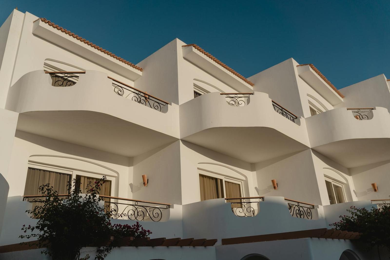 Whitewashed villa balconies with wrought-iron railings under a clear sky