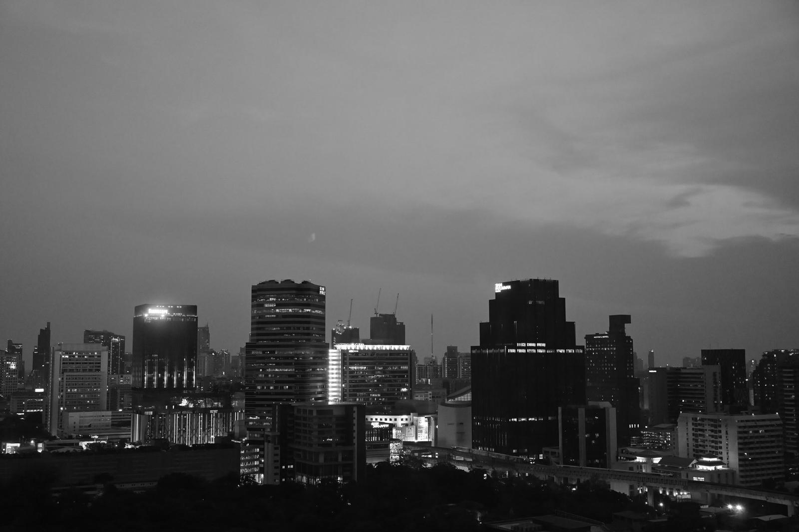 Black and white photo of a city skyline at dusk with lit office towers