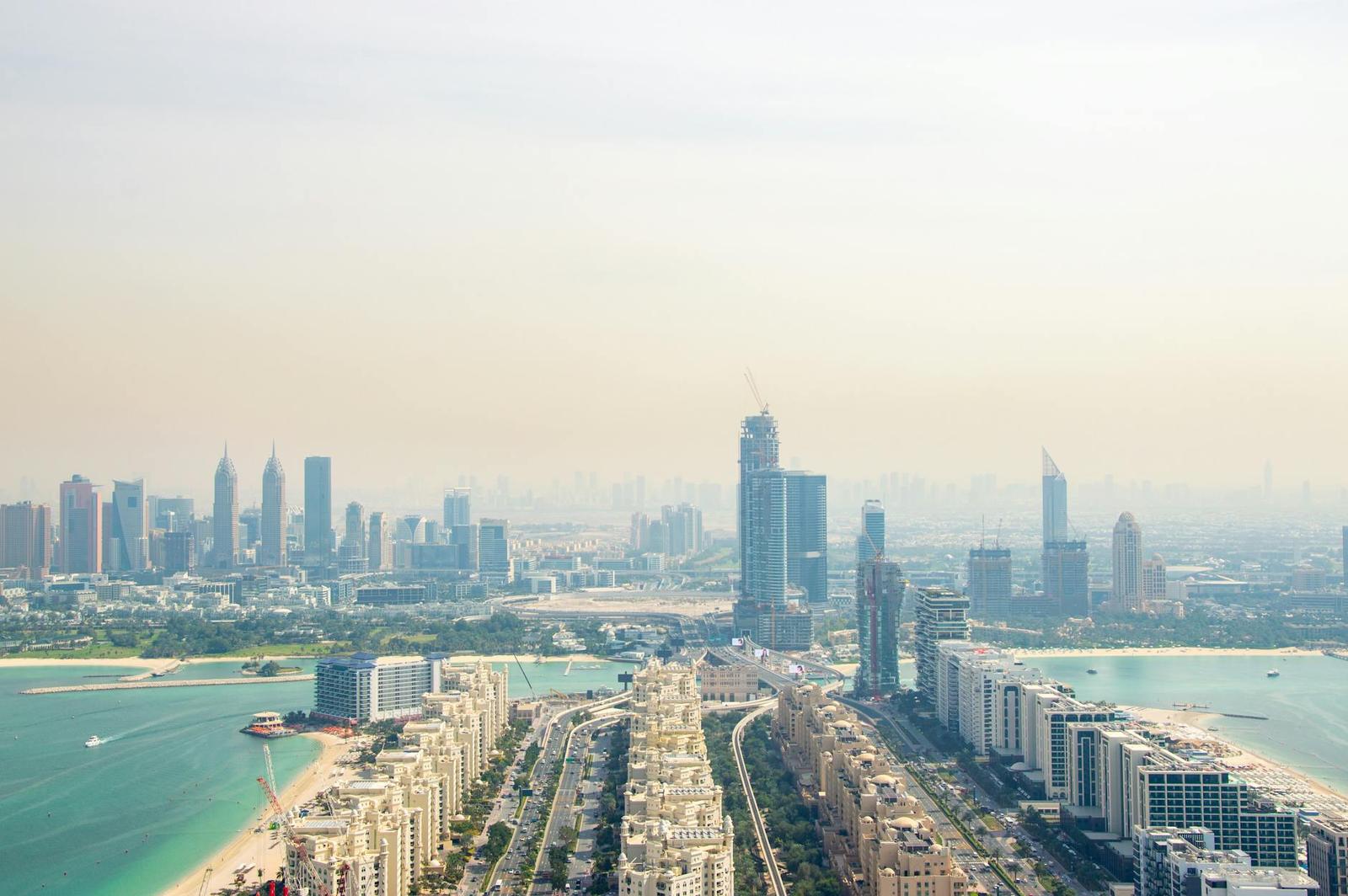 A hazy aerial view of a coastal city skyline with waterfront villas and towers