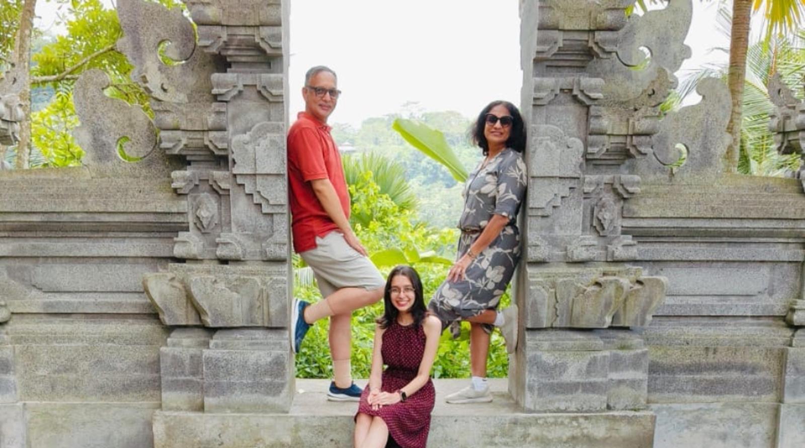 Three people posing at an ornate stone gateway with intricate carvings