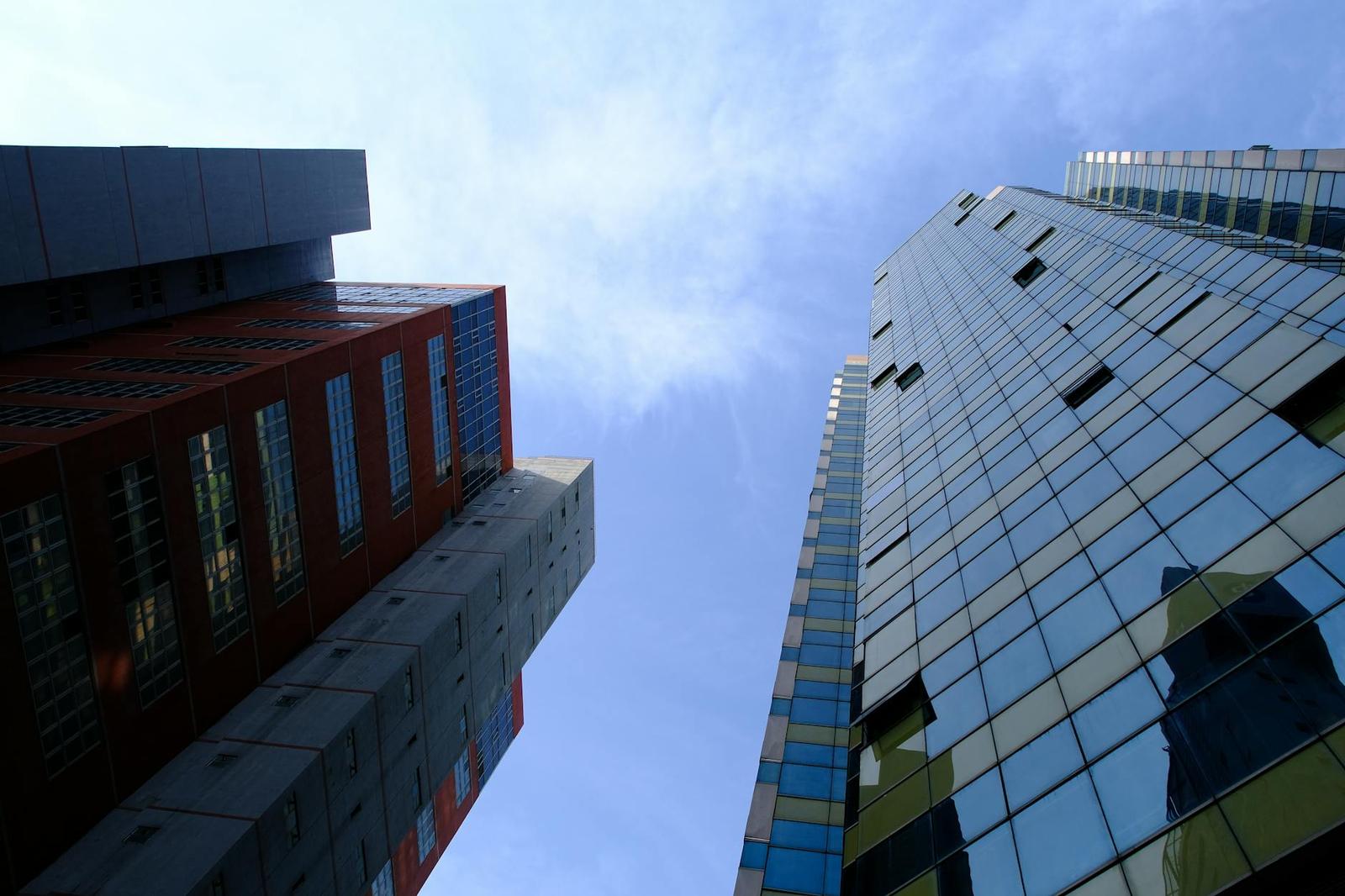 Looking up between two contrasting glass and brick high-rise towers
