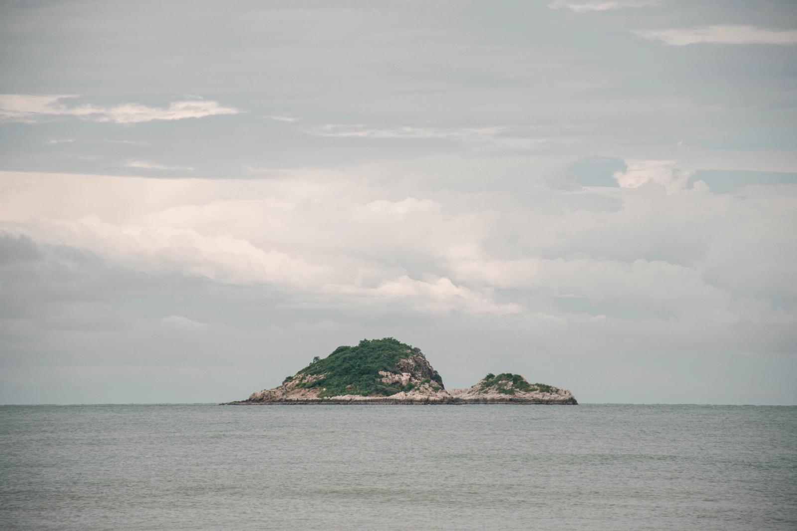 Serene view of a small island surrounded by the sea and cloudy sky in Hua Hin, Thailand