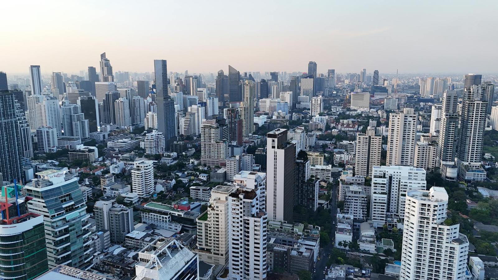 An aerial view of a dense high-rise skyline stretching to the horizon at dusk