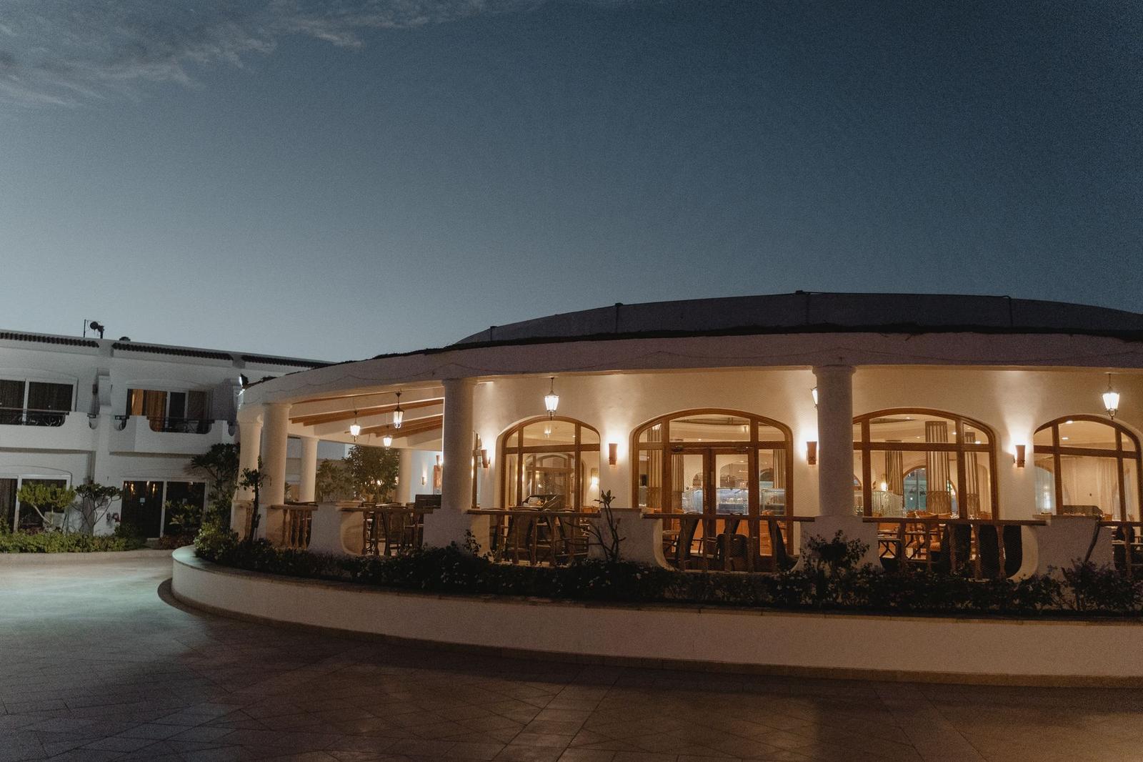 An arched veranda of a resort building lit up at dusk