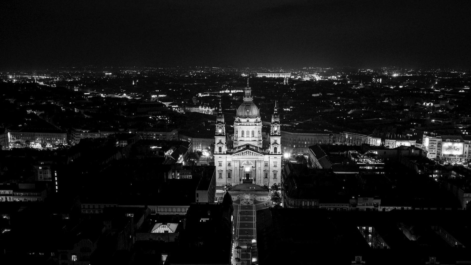Black and white aerial night view of a domed basilica lit above a dark city
