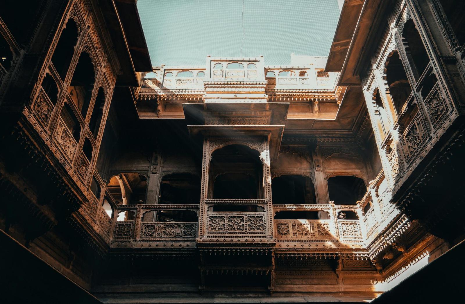 Carved wooden balconies rising around a shadowed haveli courtyard