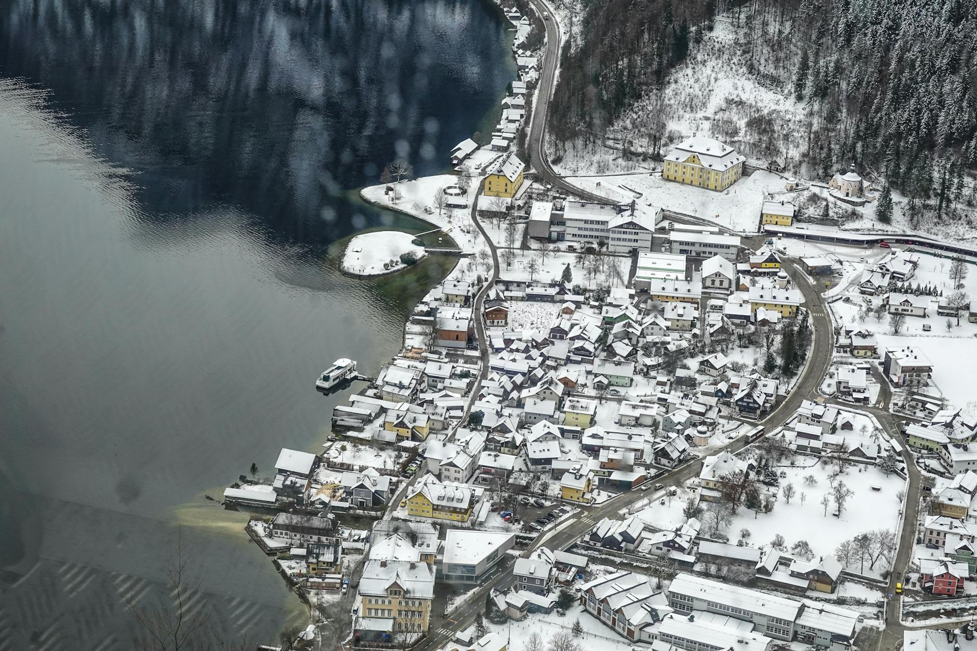Aerial view of a snow-covered lakeside village on a curved shoreline