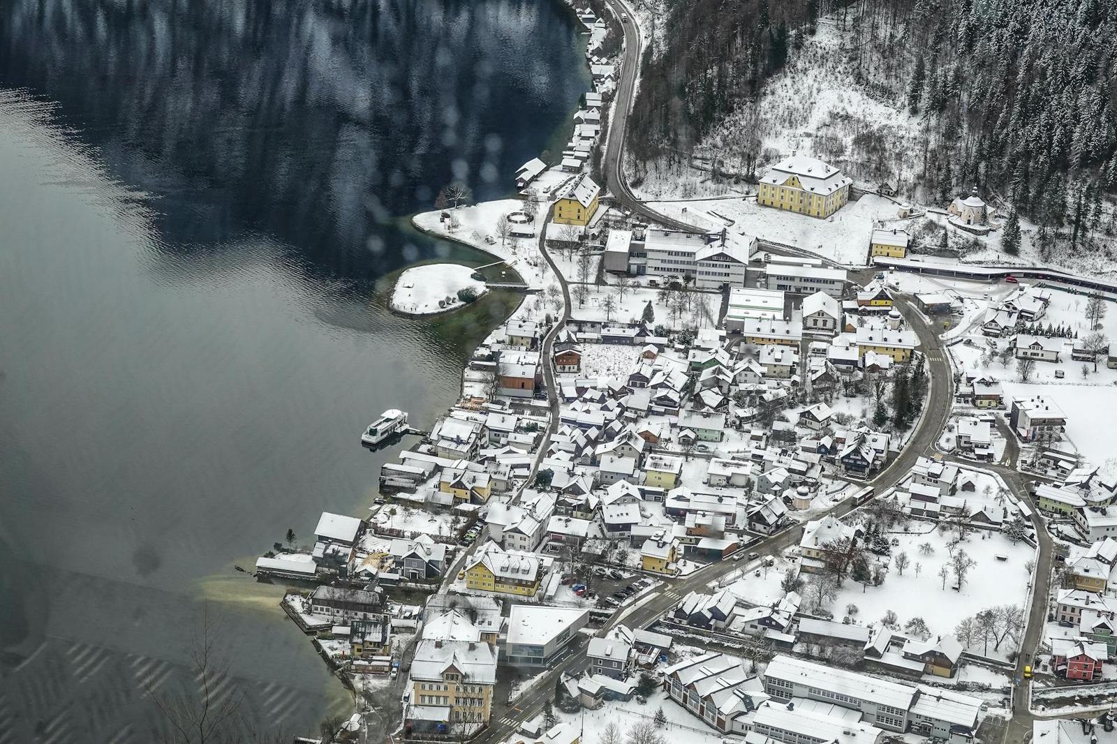 Aerial view of a snow-covered lakeside village on a curved shoreline