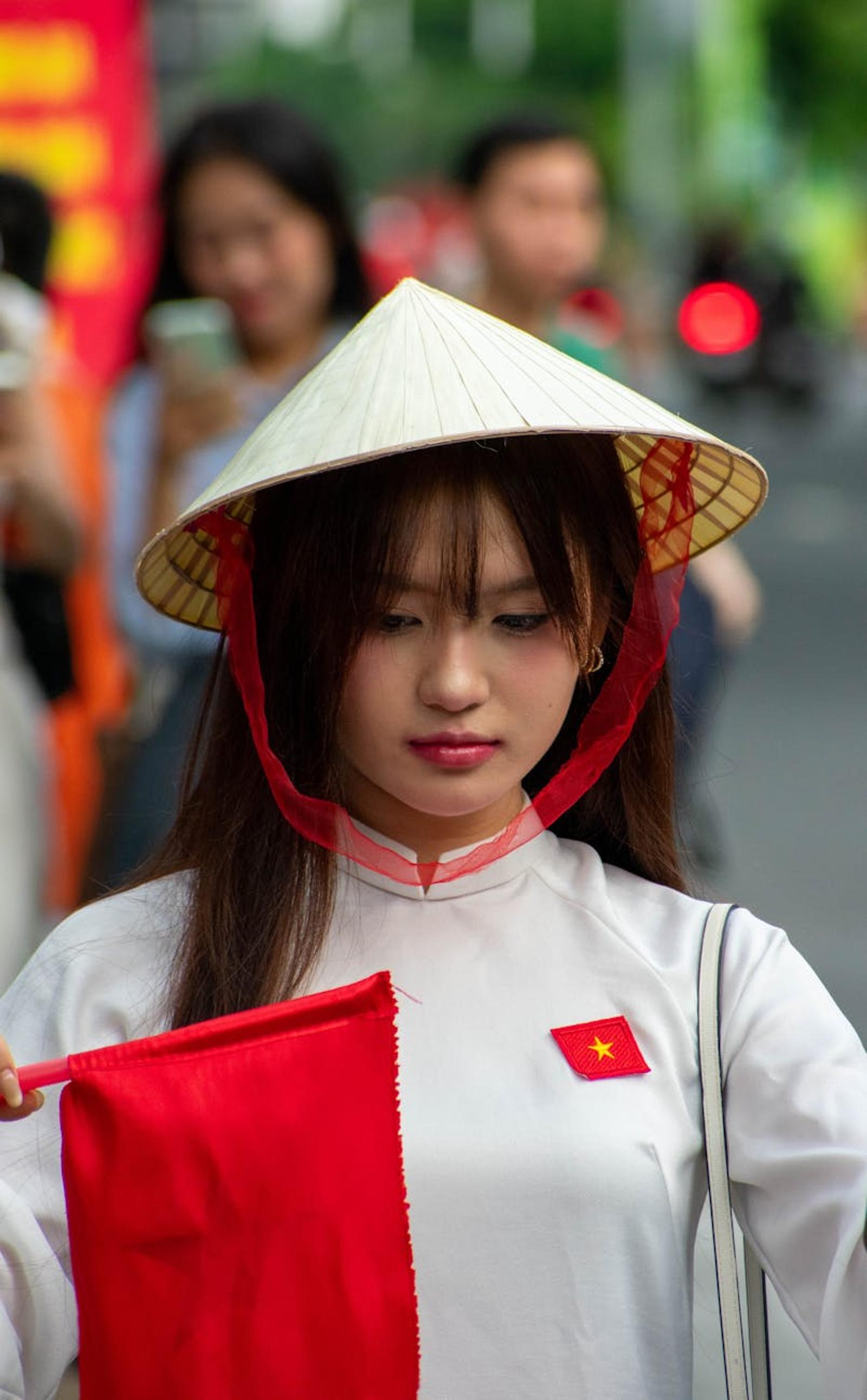 Woman in a conical hat holding a small red flag