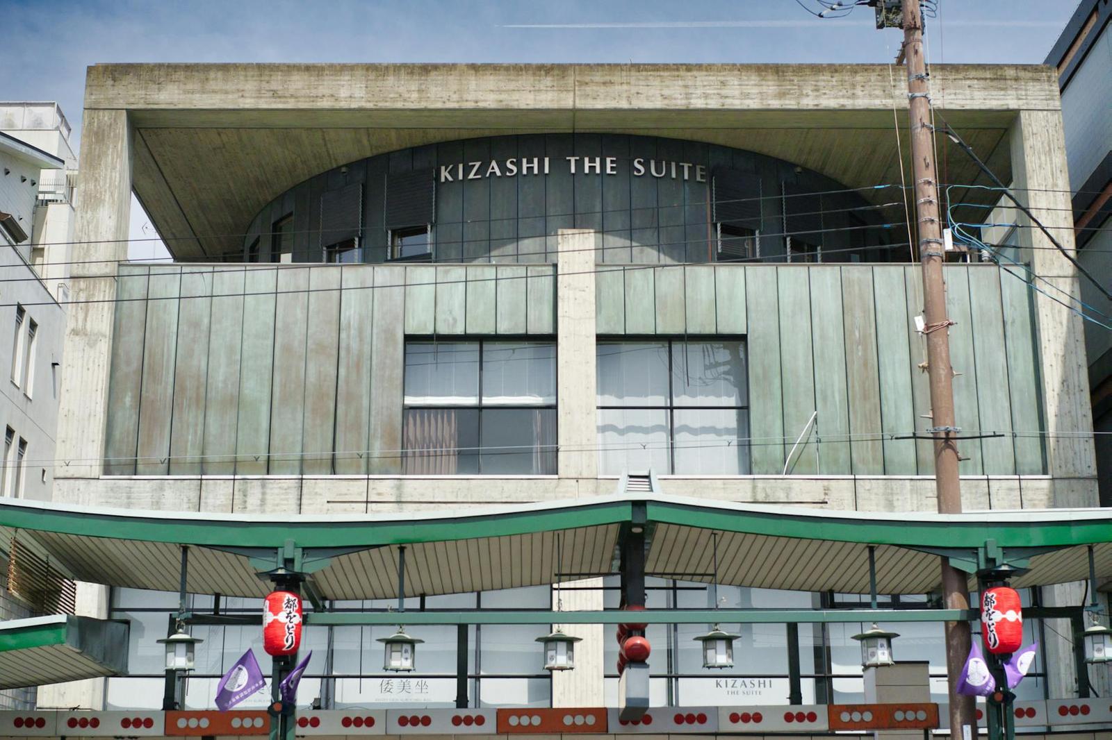 Modern hotel building facade with a curved concrete upper level and lanterns below