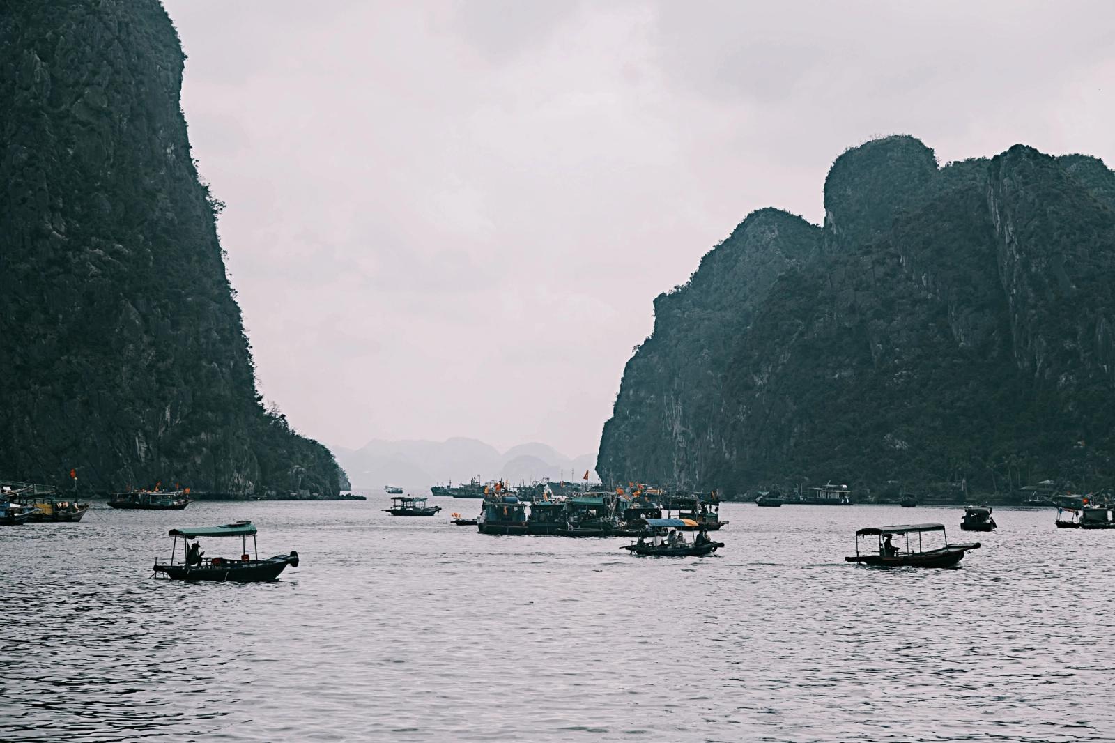 A serene view of boats sailing in the iconic limestone formations of Halong Bay, Vietnam