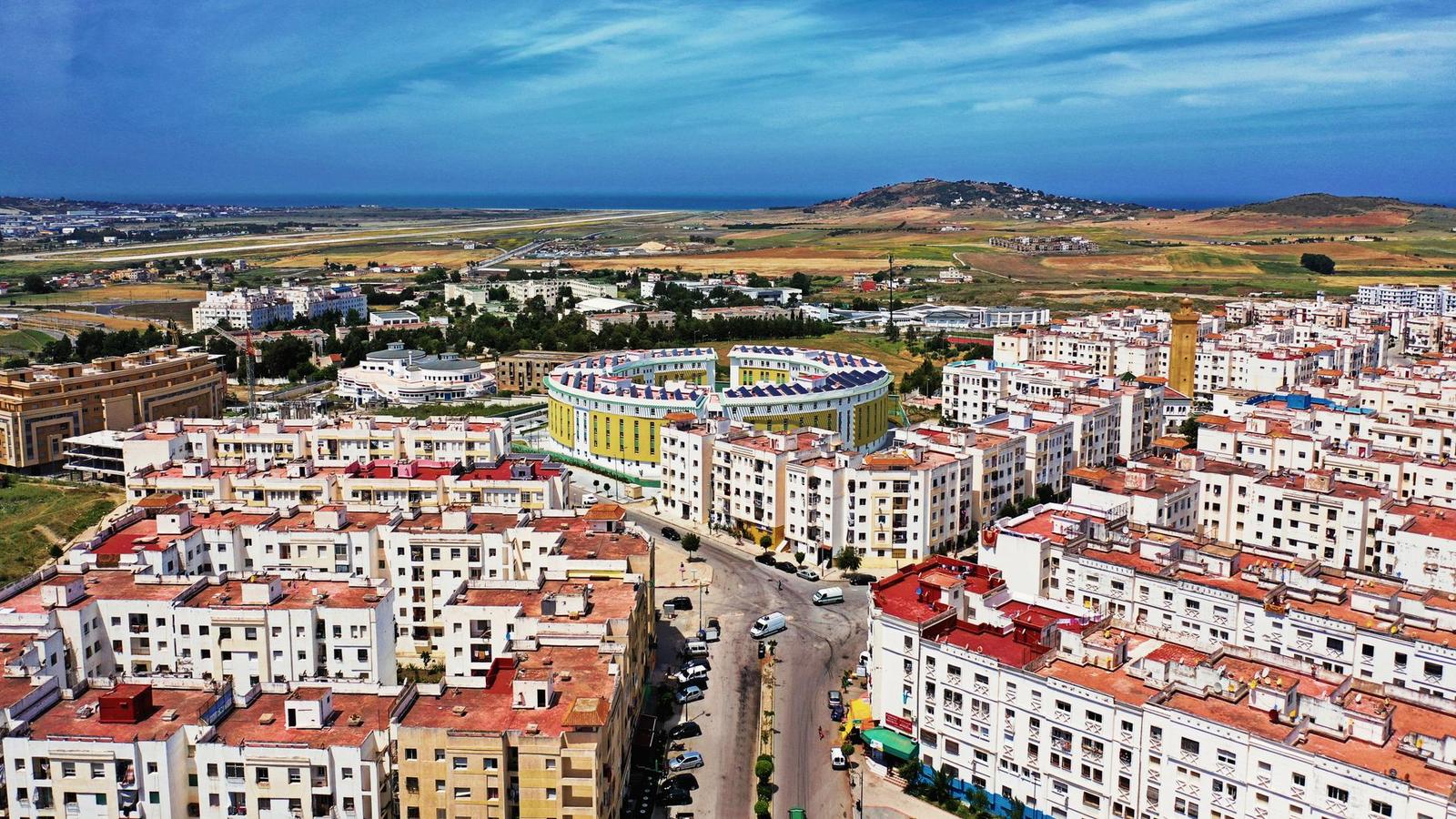 Aerial view of a coastal town with a stadium and hills beyond