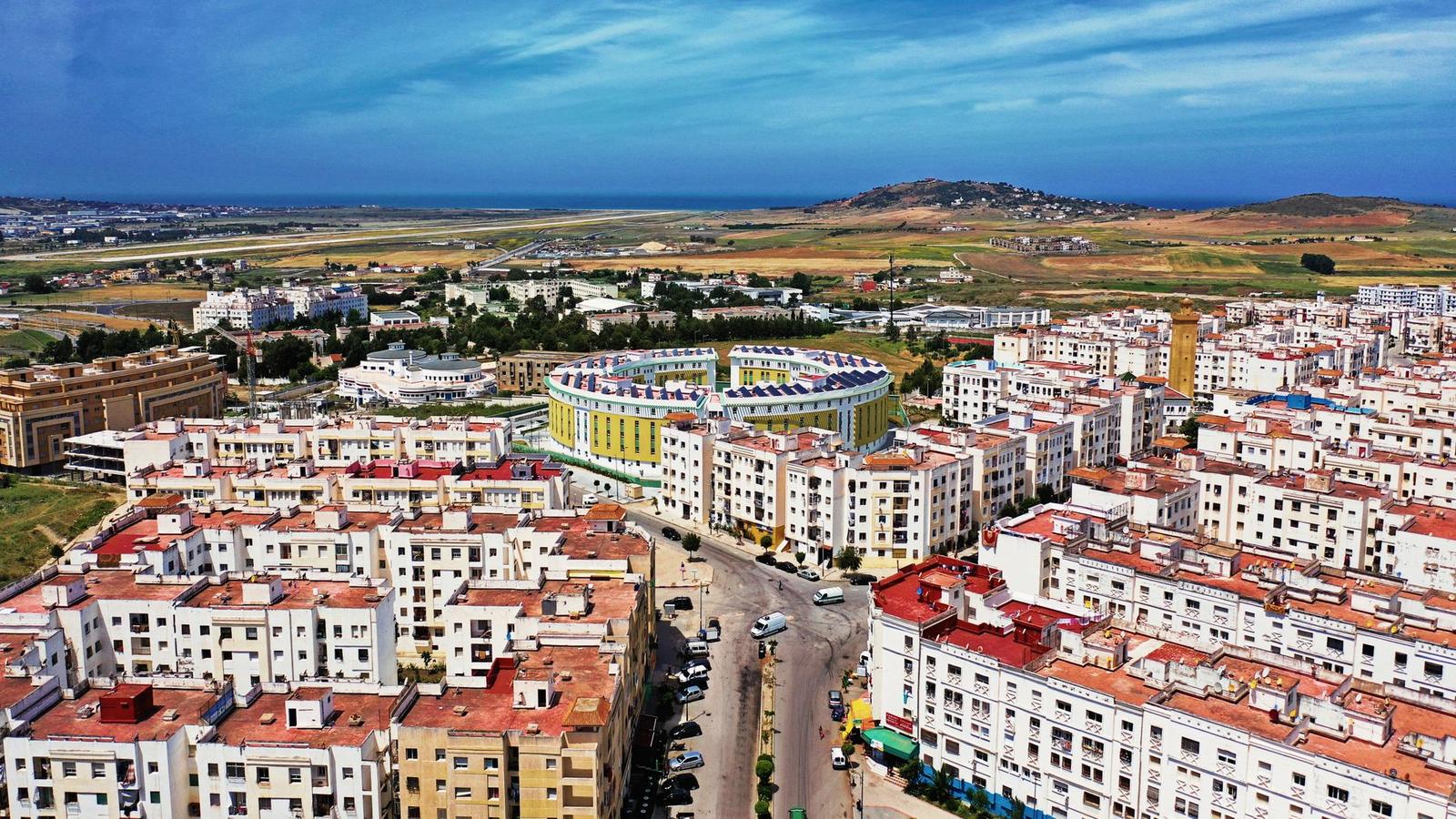 Aerial view of a coastal town with a stadium and hills beyond